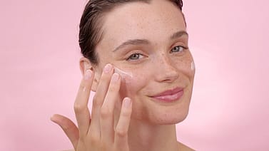 Woman applying face cream to her face