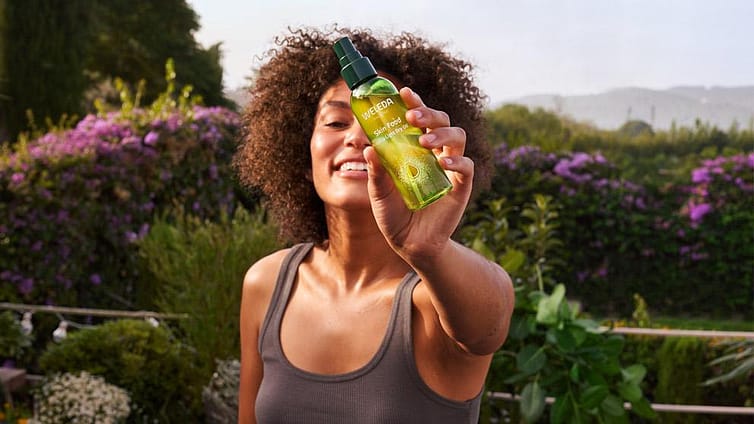 mujer mostrando aceite seco skin food de weleda