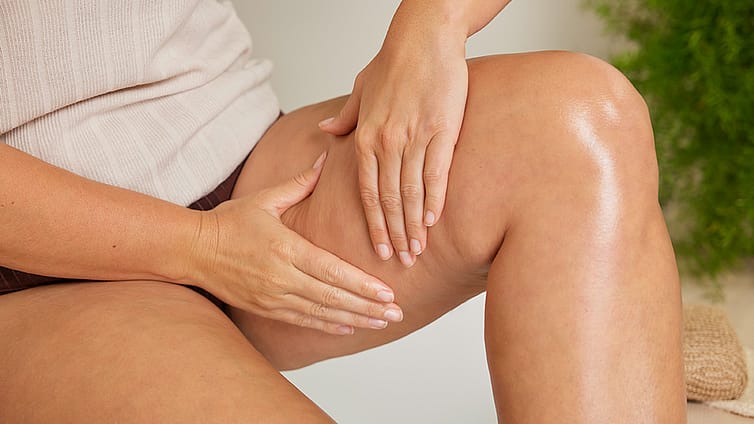 Frau massiert das Birken Cellulite Öl ins Bein ein