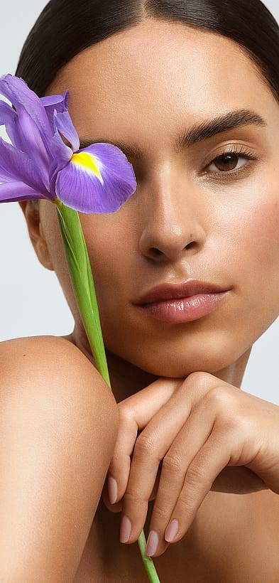 Frontale Ansicht einer Frau mit Blume, die sie vor das Gesicht hält