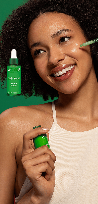 Frau mit dunklen Haaren und strahlendem Lächeln sowie Abbildung des Weleda Skin Food Super Serums