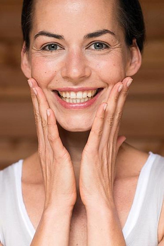 lachende frau hält beide hände ans gesicht