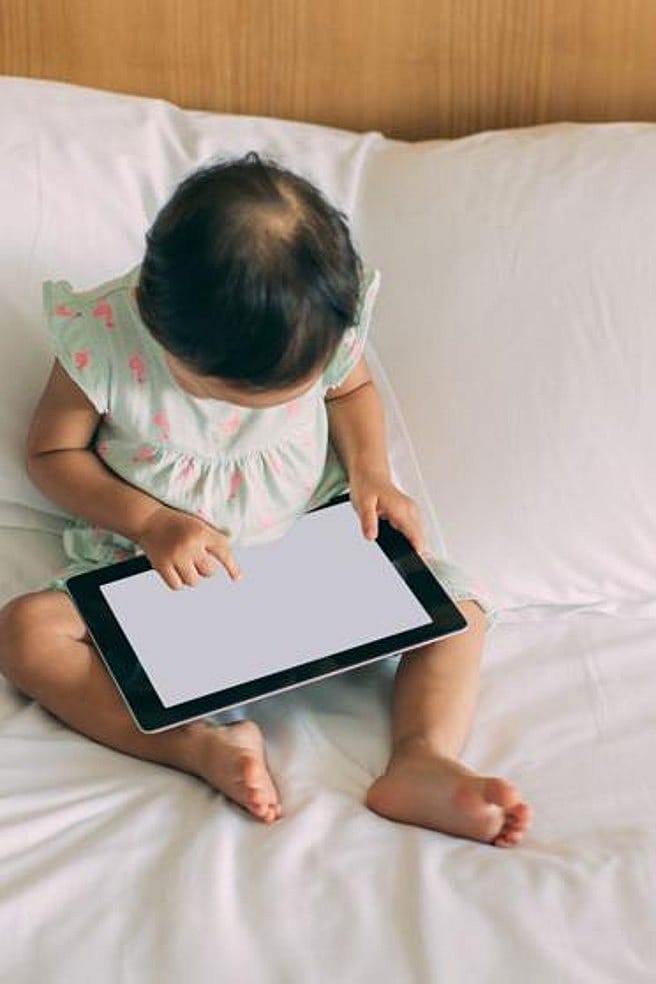 Kind sitzt vor einem Tablet Bildschirm