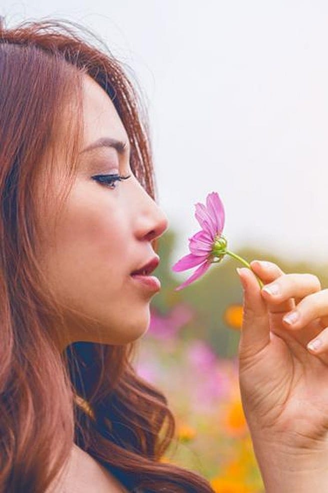 Frau riecht an einer Blume