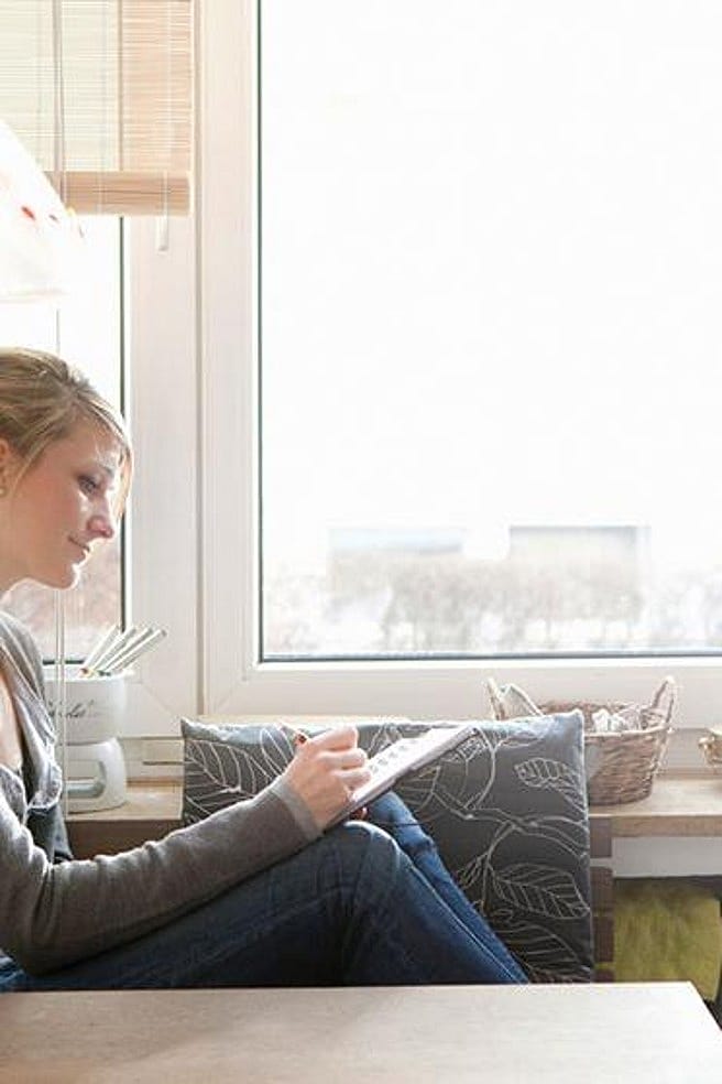 Frau auf dem Sofa macht sich Notizen