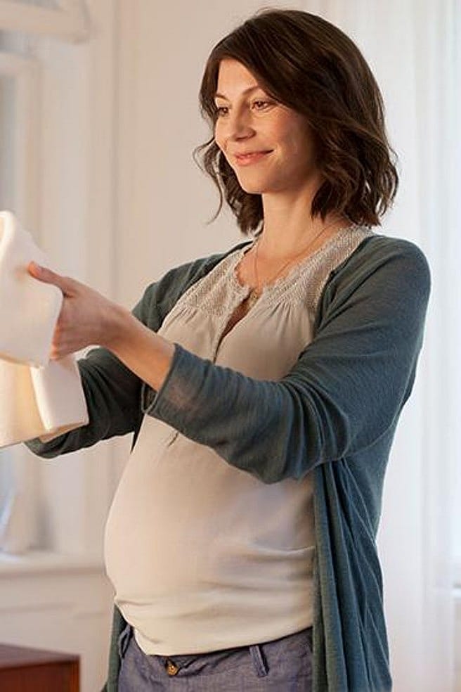 Frau hält Babykleidung in der Hand