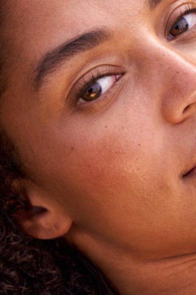 Vrouw die crème smeert op haar wang