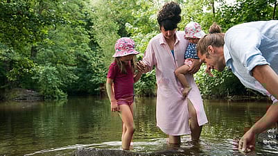 Famiglia con piedi e gambe nel laghetto guardano il fondo dell'acqua