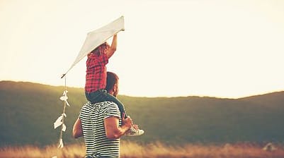 fille sur les épaules du père avec cerf volant
