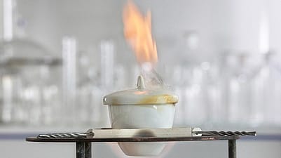 Porzellangefaess mit Deckel ueber einer Flamme