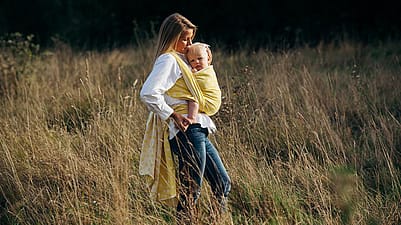 Donna tiene in braccio un bambino mentre è in un campo