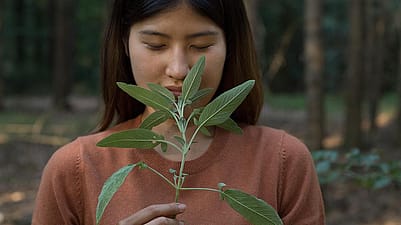 Donna annusa delle foglie con gli occhi chiusi