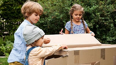 niños jugando con una caja de cartón