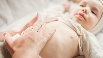 bebé tumbado recibiendo un masaje en la tripita