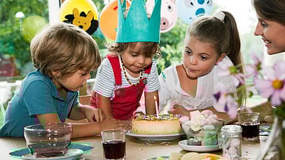 niños celebrando alrededor de una mesa, donde hay una tarta
