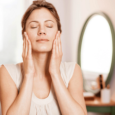 mujer aplicándose crema en el rostro