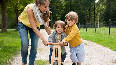 familia ayudando a uno de sus hijos a montar en bici