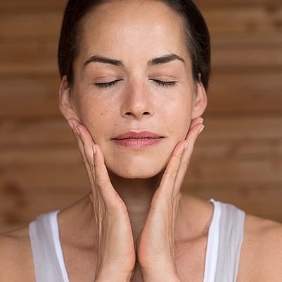 mujer realizándose un masaje facial