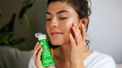 Junge Frau trägt Weleda Skin Food als Highlighter auf