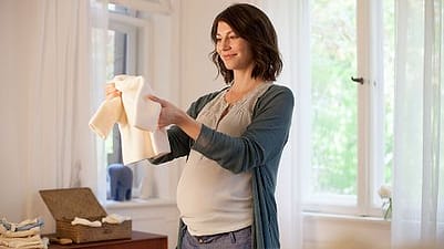 Frau hält Babykleidung in der Hand