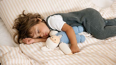 niño dormido en el sofá con su peluche