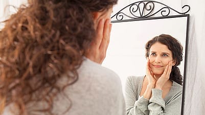 Une femme se regarde dans le miroir.