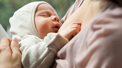 bebé con los ojos cerrados tomando pecho