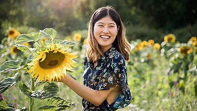 woman smiling holding sunflower in a field