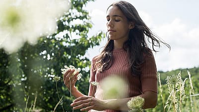 Une femme observe les fleurs d'une espèce de graminée