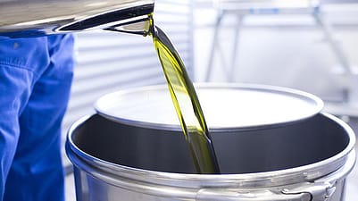 trabajador vertiendo aceites esenciales en un bidón