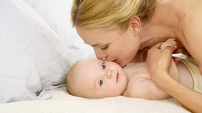 mujer dándole un beso en la mejilla a un bebé