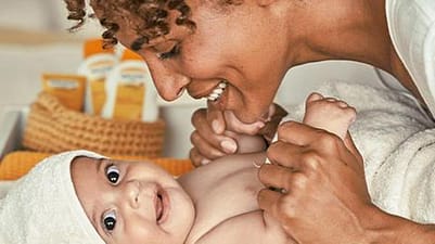 mujer abrazando a un bebé que está tumbado con la toalla puesta