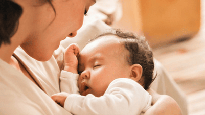 mujer sosteniendo a un bebé dormido en los brazos