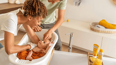 un hombre y una mujer bañando a un bebé en una bañera