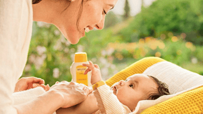 mujer dando un masaje al bebé mientras le aplica aceite corporal