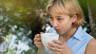 Frau trinkt im Garten Tee