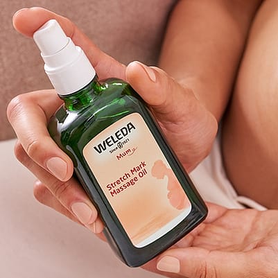 Gravid kvinna håller i Weleda Stretch Mark Massage olja