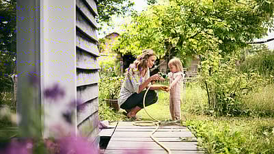 Frau lindert Stich mit Gartenschlauch