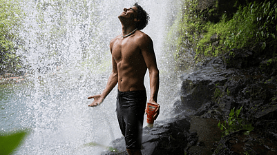 hombre en mitad de la naturaleza con una cascada en el fondo