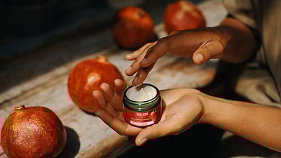 Frau hält Weleda Straffende Tagespflege geöffnet in der Hand und entnimmt die Tagescreme