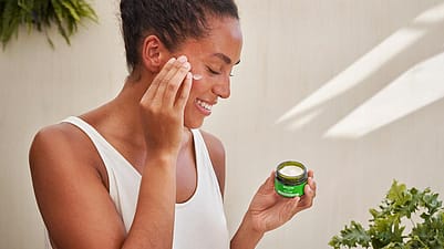 mujer sonriendo mientras se aplica la crema de día de skin food