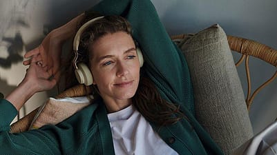 Frau liegt entspannt und hört Musik mit Kopfhörern