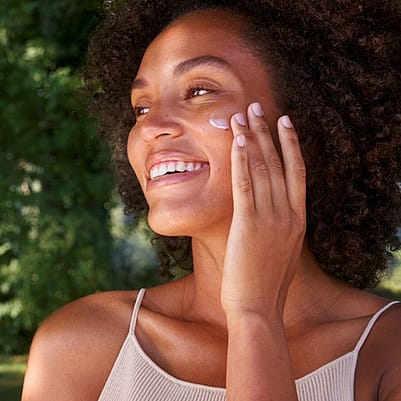 mujer aplicándose crema en el rostro