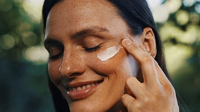 femme qui s'applique de la crème sur la joue