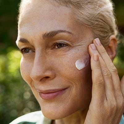 mujer aplicándose crema en el rostro
