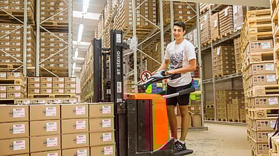 Mann auf Gartenstapler im Lager