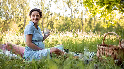 Schwangere Frau im Grass mit Kissen und zu trinken
