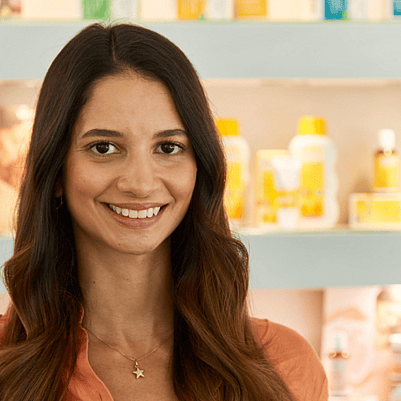 Mitarbeiterin vor Weleda Produkten