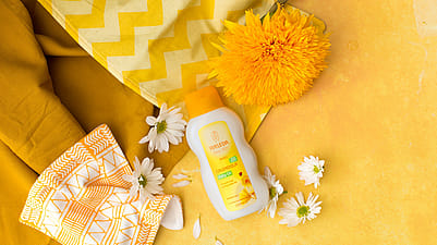 aceite corporal de bebé de calendula al lado de una flor de calendula