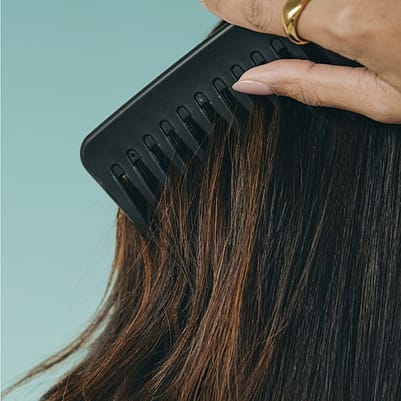 Cabello siendo cepillado por un peine negro